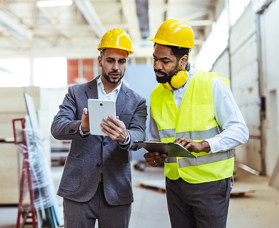Profissionais em ambiente industrial avaliando informações em um tablet
